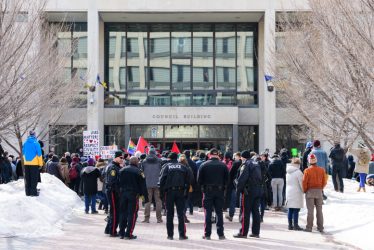 Photo of police supervising two simultaneous protests at Winnipeg City Hall.