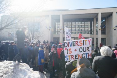 Photo of counter-protesters and their signs in from of Winnipeg City Hall.