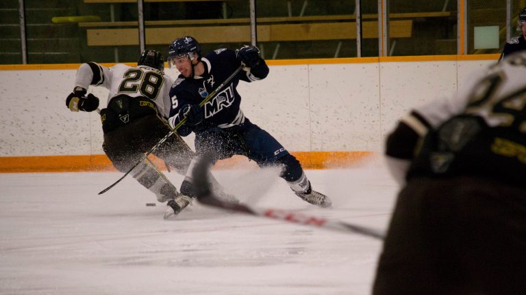 Bison captain Brett Stovin regains puck possession on Mount Royal defence man Shane Poulsen.