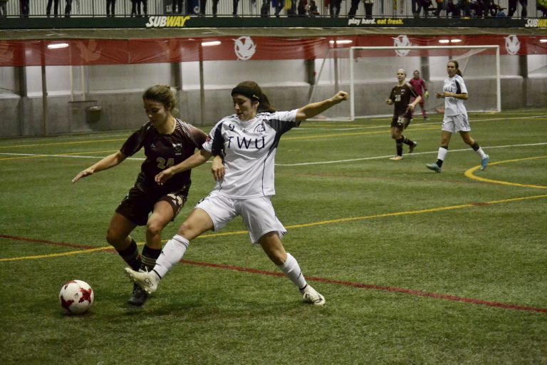 Bison defender Hayley Ward fights off Spartan forward Seina Kashima during their quarterfinal matchup. Trinity Western won 4-0.