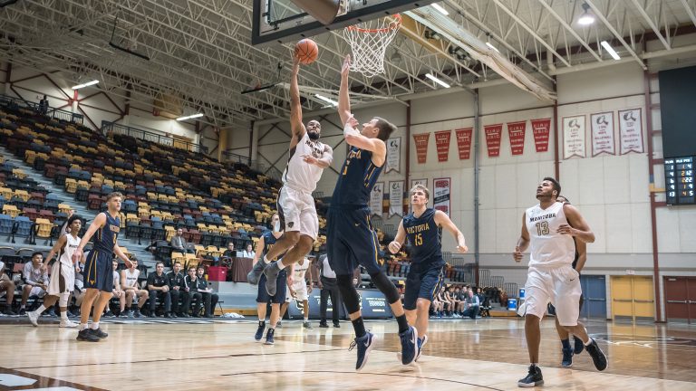 Bison captain Justus Alleyn (#6) drives for the lay up past Victoria’s Jake Newman (#6) on Jan. 13 at the Investors Group Athletic Centre.