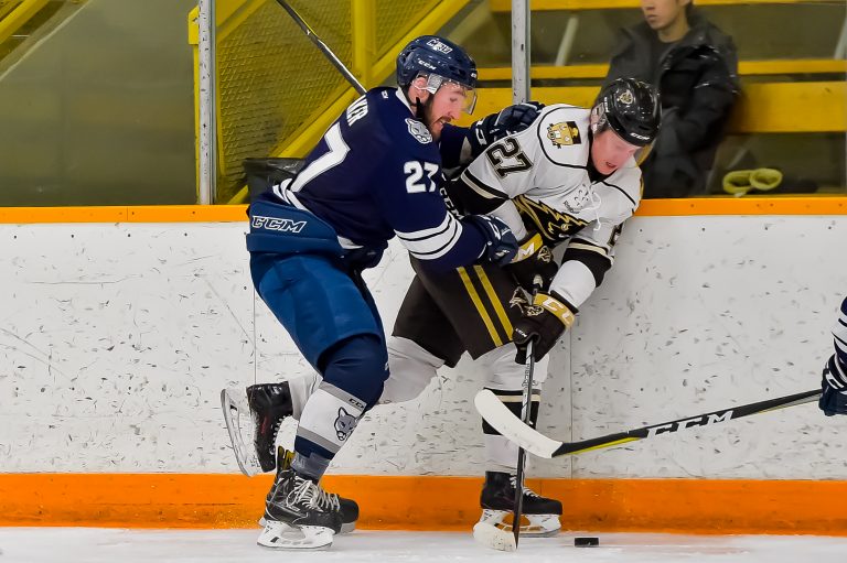 Bison forward Zach Franko is checked by Cougar defenceman Grant Baker during Canada West quarter final action at the Wayne Fleming Arena in Winnipeg.